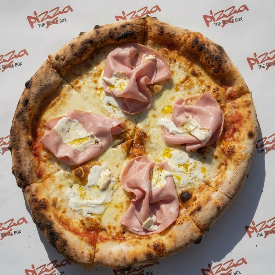 A whole Pizza The Box pizza with mortadella, burrata, and olive oil, on a branded paper.